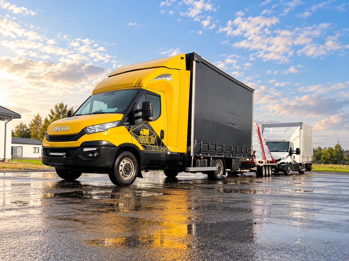 Geltonas Siunta777 „Iveco“ su tentiniu kėbulu ir priekaba su plėvele apvyniotais kroviniais; už jų – baltas „Iveco“