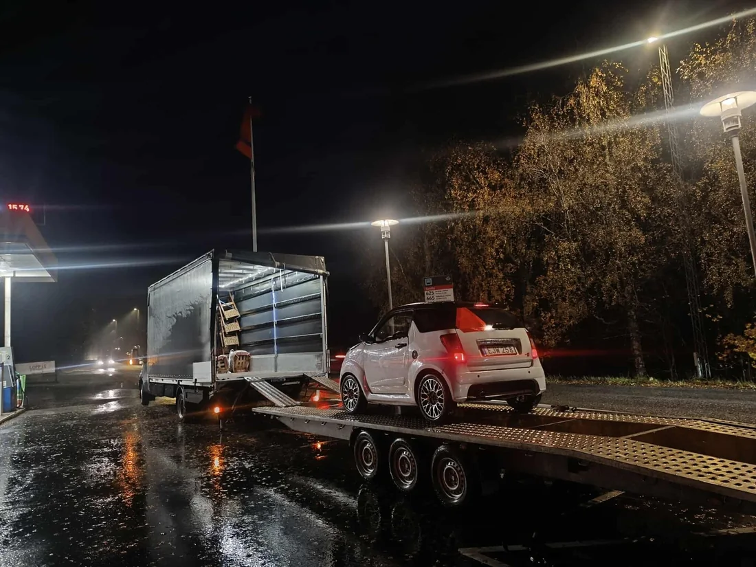 Baltas automobilis ant automobilių tralo naktį