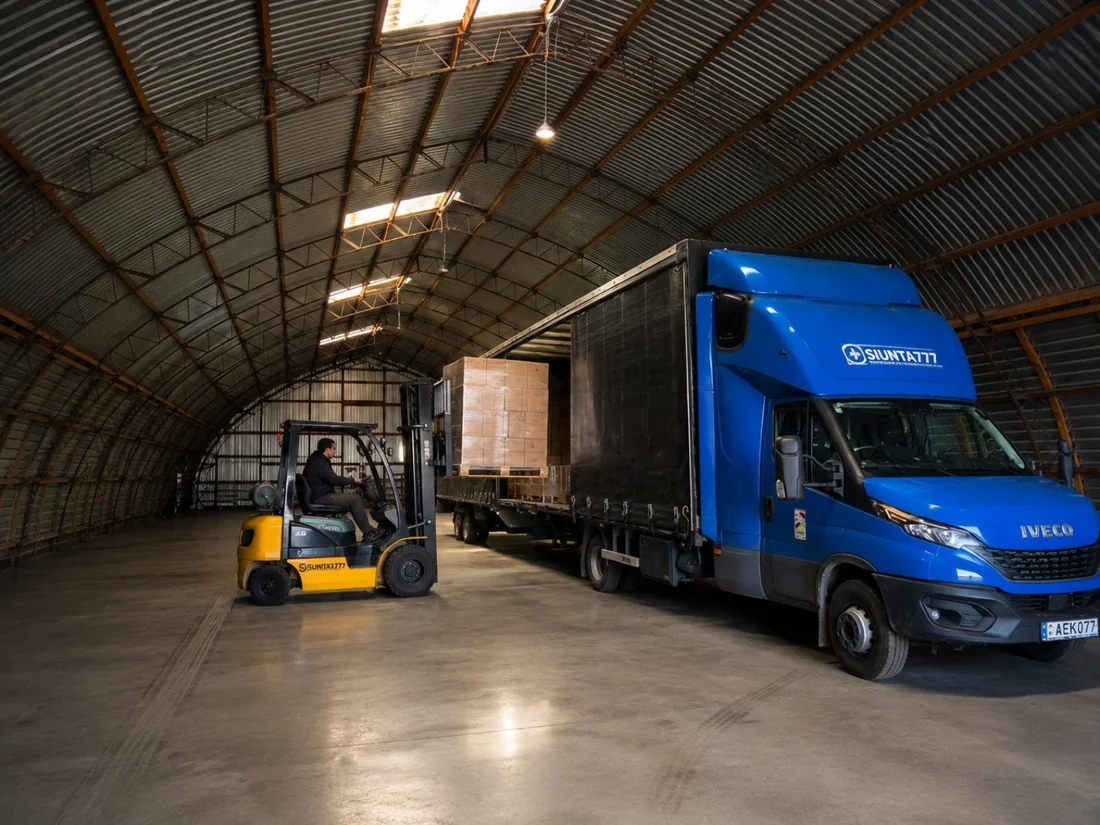 Mėlynas Siunta777 „Iveco“ sunkvežimis ir šakinis krautuvas sandėlyje