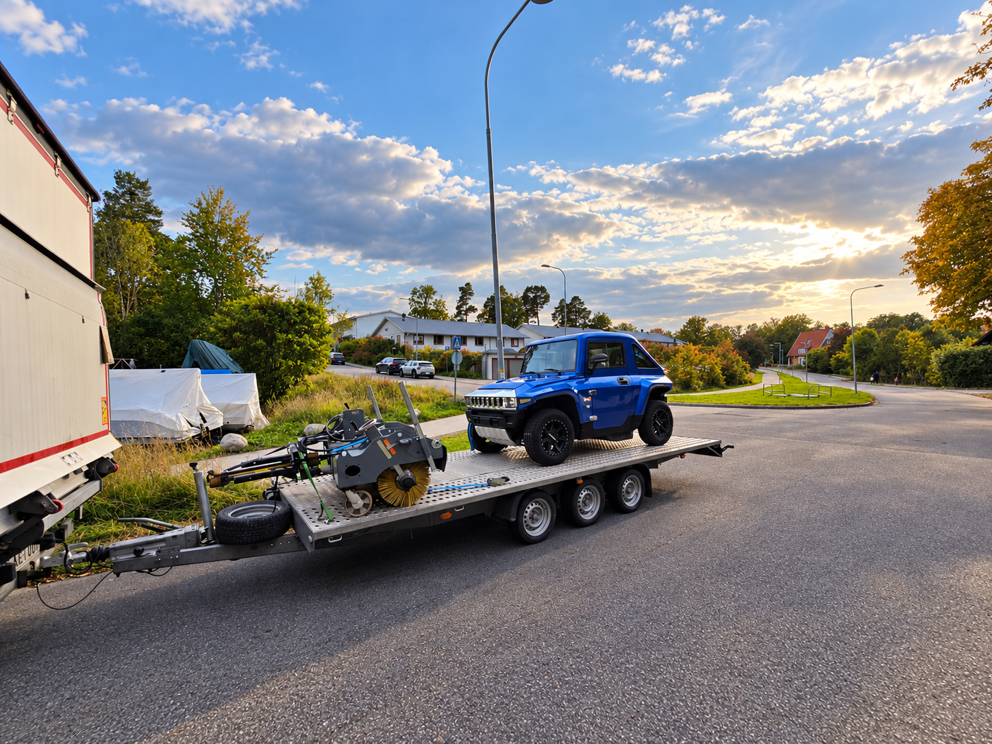 Mėlynas visureigis ir technika ant automobilių tralo
